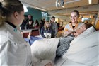 Bezoekers van een open dag van een ROC staan rond een ziekenhuisbed met een pop erin