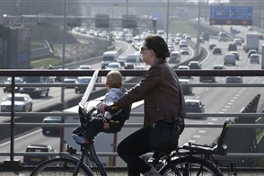 Nederland, Rotterdam, fietser moeder met kind op viaduct over de A20, een van de drukste snelwegen van Nederland