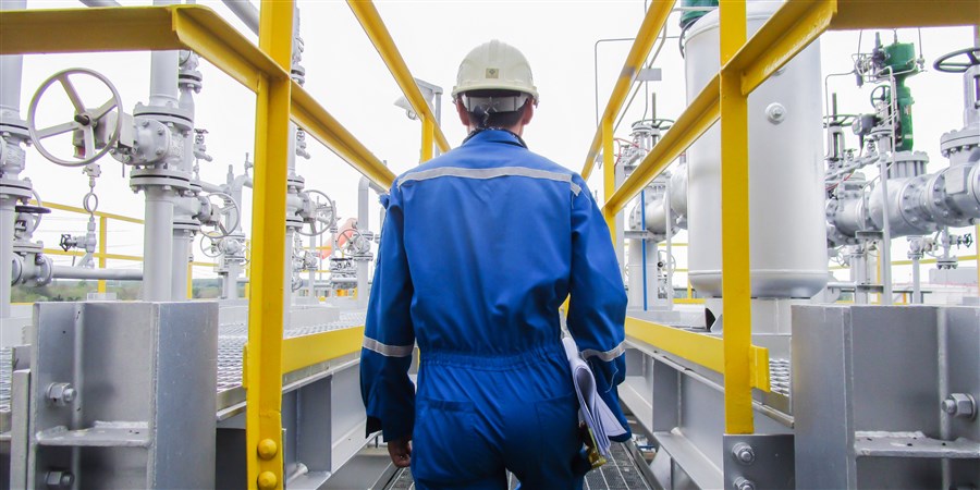 Alt-tekstMedewerker inspecteert op de olieraffinaarderij