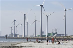 Klein recreatiestrand met windmolens en industriegebied op de achtergrond