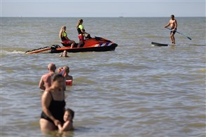 Two members of the Maritime Rescue Squad on a jet ski speak to a man on an SUP paddle.