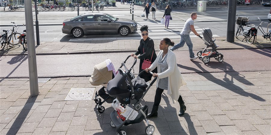 Vriendinnen lopen met hun kinderen in een wandelwagen door het centrum van Rotterdam.