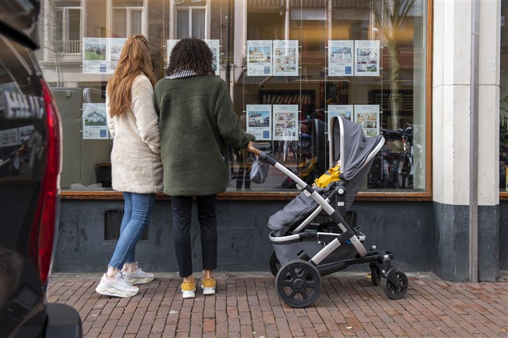 People looking information about homes for sale in an estate agent's window