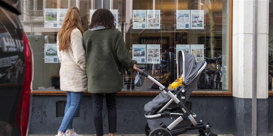 People looking information about homes for sale in an estate agent's window