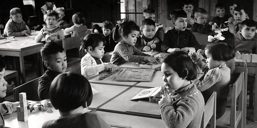 Jonge evacué's uit Indonesië aan een aparte tafel in een schoolklas in Amsterdam Slotermeer| Nationaal Archief