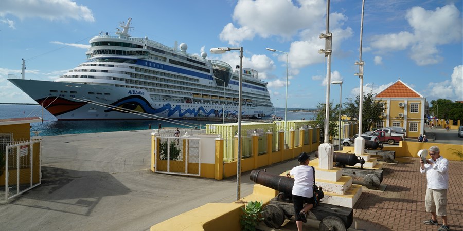 Cruise ship and tourists in harbour Kralendijk with old cannon in Bonaire.