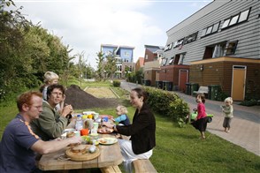 ouders lunchen met hun kinderen in het groen van een ecowijk.