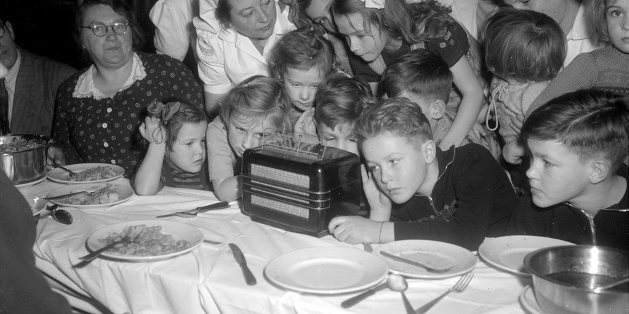 Nederlanders luisteren naar radioberichten over de watersnoodramp in 1953
