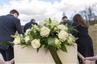 Bloemen liggen op kist bij natuurbegrafenis