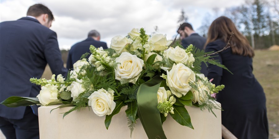 Bloemen liggen op kist bij natuurbegrafenis