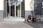 Een dakloze man die op het Leidseplein tegen een muur aanzit.
