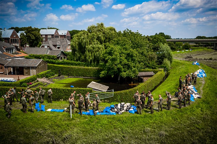 Militairen ruimen de zandzakken op die een dorp moesten beschermen tegen de mogelijke overstroming van de Maas