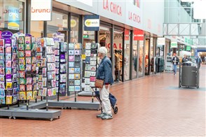 een oudere vrouw die naar kaarten kijkt in een winkelcentrum