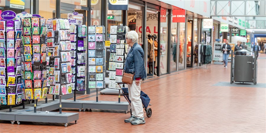 een oudere vrouw die naar kaarten kijkt in een winkelcentrum