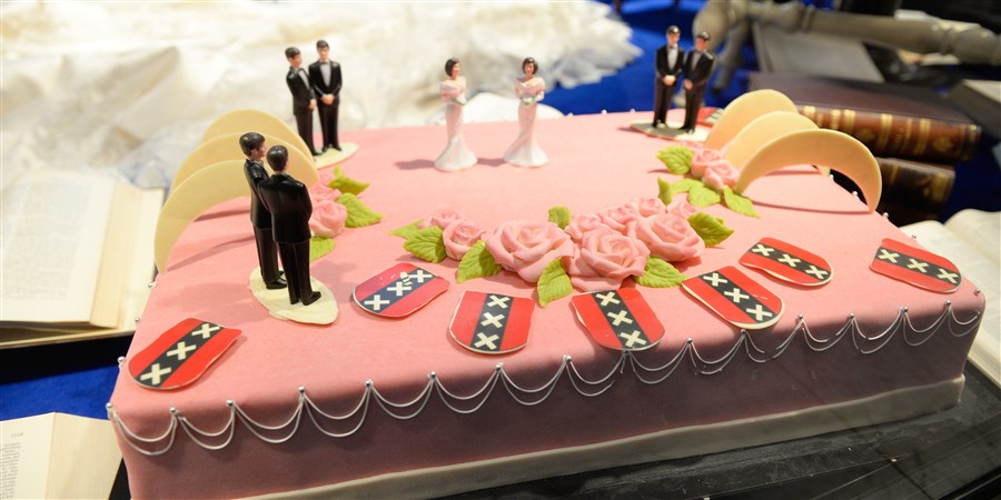 Roze huwelijkstaart met poppetjes erop die het homohuwelijk verbeelden