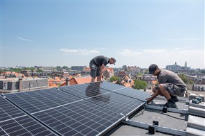 Men install solar panels on a roof