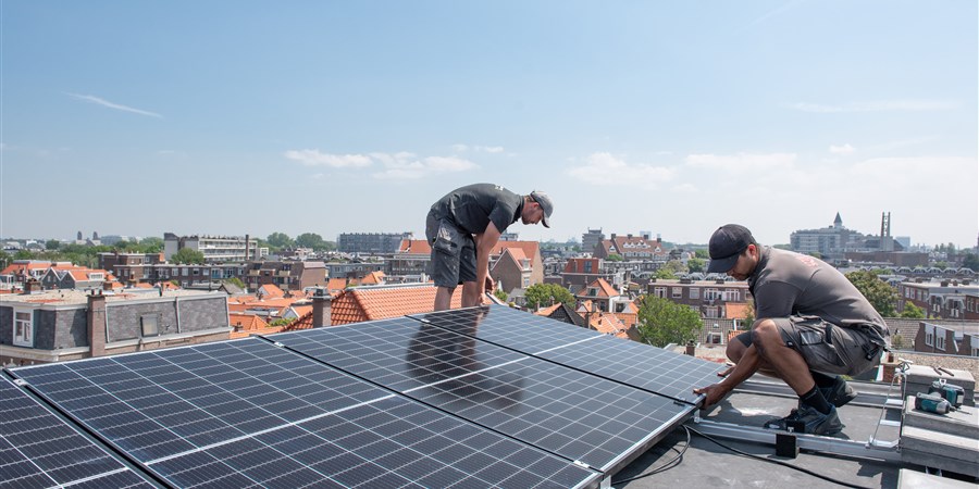Mannen installeren zonnepanelen op een dak