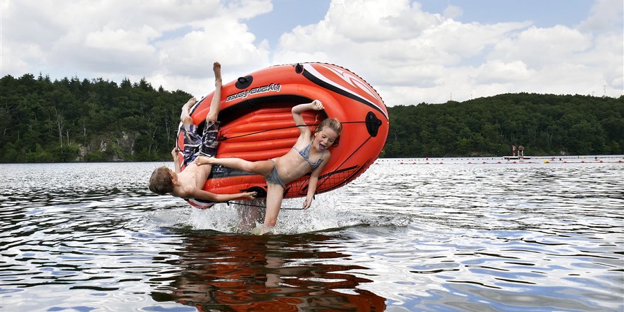 Een jongen en meisje vallen uit rubberbootje dat door hun vader in de lucht wordt omgegooid. Ze zijn op vakantie in Frankrijk en spelen en in het water.