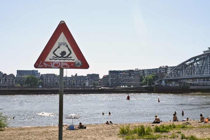 Op het Waalstrand in Nijmegen wordt met een bord gewaarschuwd dat het onverstandig is om tussen kribben van de rivier te zwemmen.
