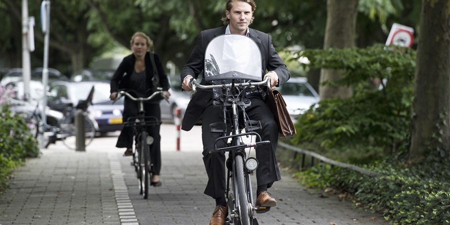 Jonge ambitieuze man op fiets met kinderzitje Amsterdamse Zuidas