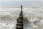 Vrouw balanceert op strandhoofd tussen golven