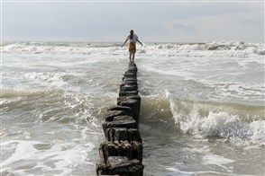 Vrouw balanceert op strandhoofd tussen golven