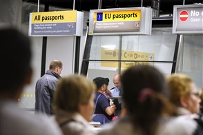 Travellers waiting in front of the passport control desk at Amsterdam Schiphol Airport