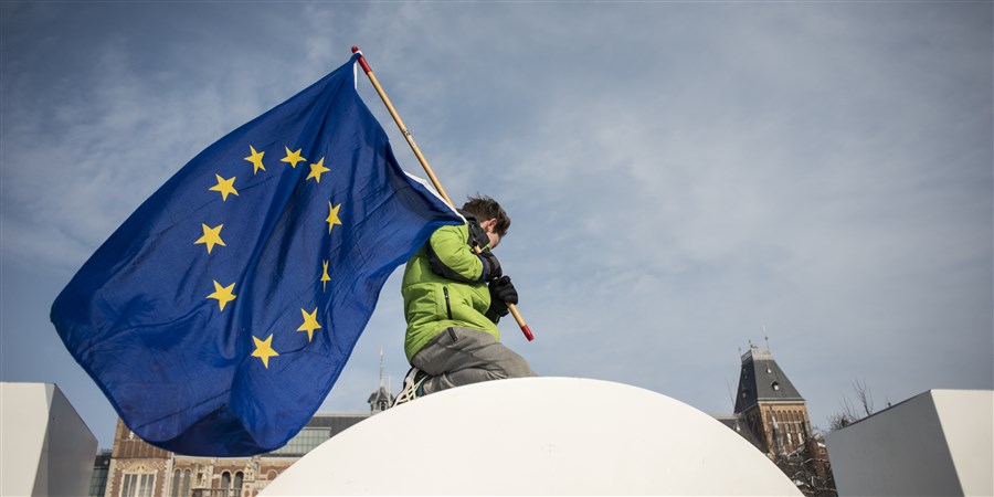 Jongetje plant Europese vlag op een dak.