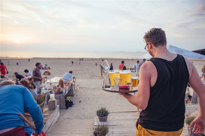 Kelner met drankjes op terras aan het strand