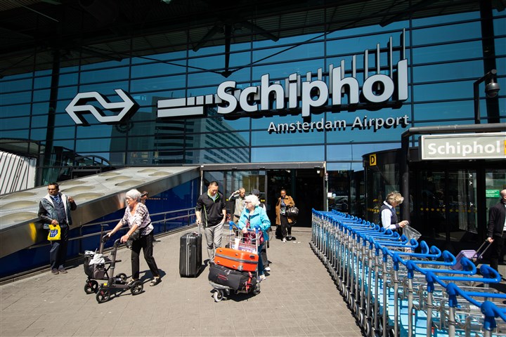 Aangekomen reizigers op Schiphol lopen het gebouw uit