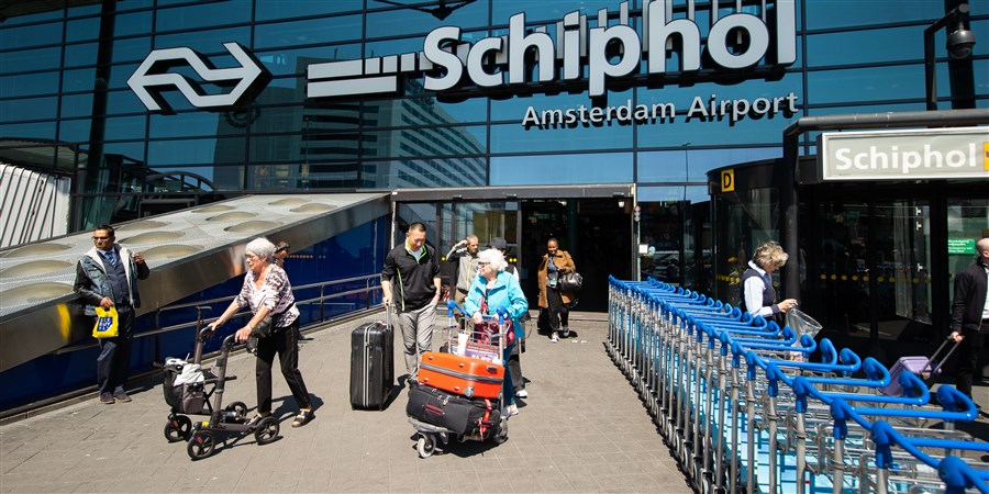 Aangekomen reizigers op Schiphol lopen het gebouw uit