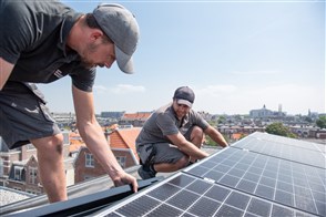 Men installing solar panels on the roof of a house.