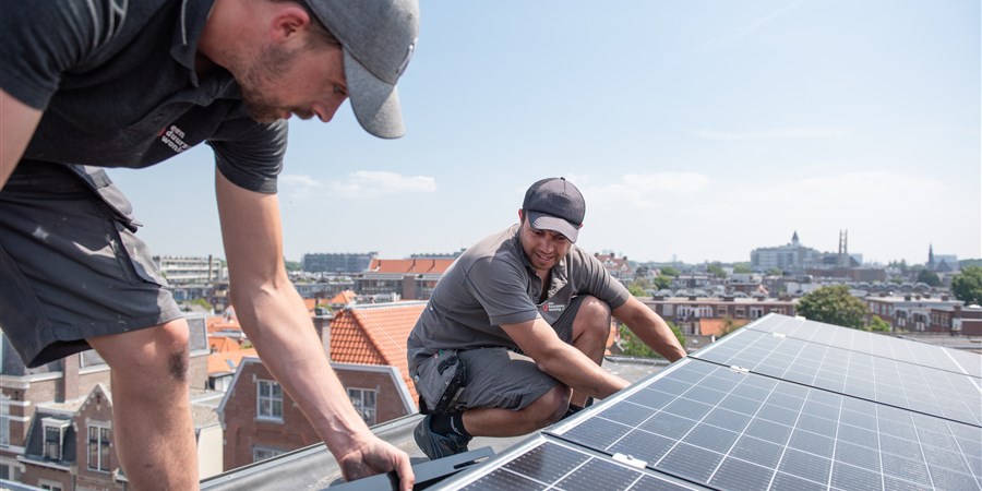 Men installing solar panels on the roof of a house.