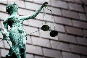 Bij een rechtbank staat een beeldje van vrouwe justitia op het dak