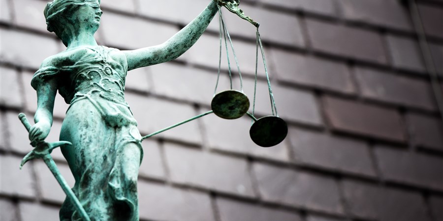 Bij een rechtbank staat een beeldje van vrouwe justitia op het dak