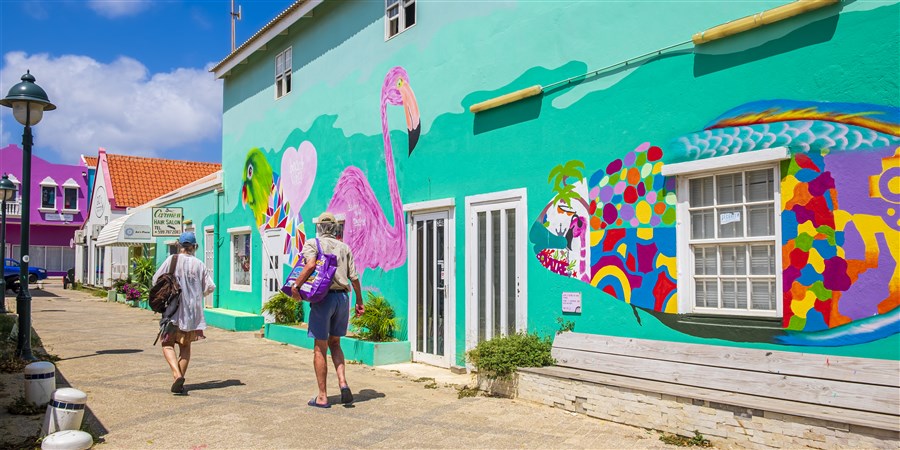 Toeristen lopen door een kleurrijke straat van Kralendijk, hoofdstad van het Caribisch Nederlandse eiland Bonaire.