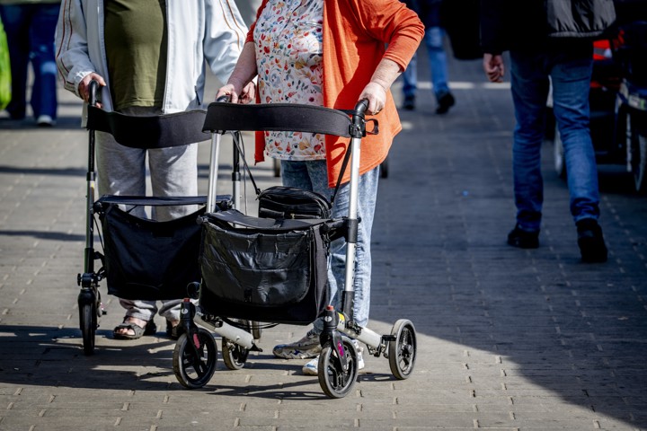 Oudere man en vrouw achter een rollator op straat.