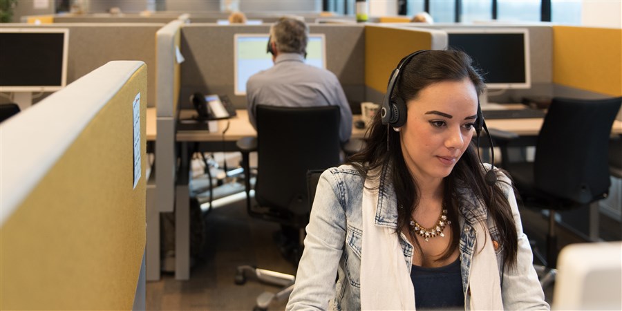 Vrouw met koptelefoon aan het werk in het CBS Contact Center in Heerlen