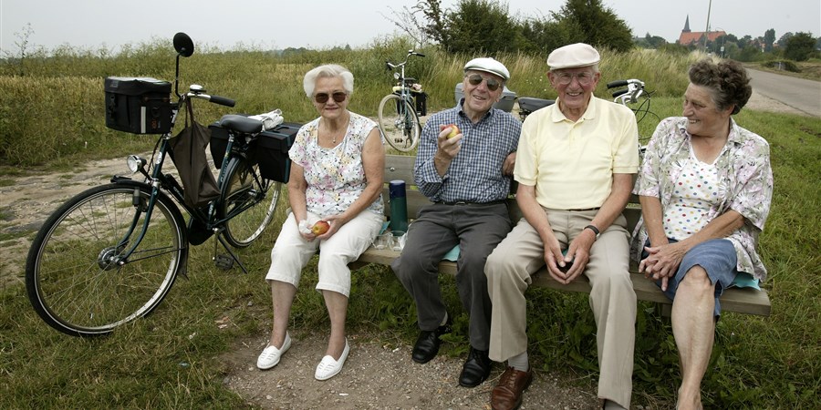 Ouderen rusten uit van fietstochtje op een bankje
